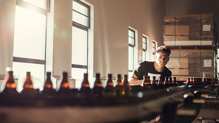Brewer supervising the bottling process by checking his production line.