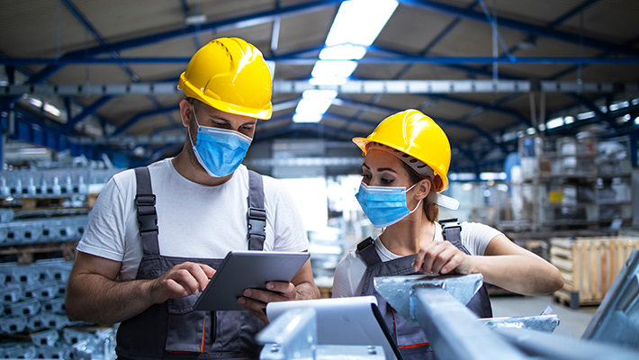 Des travailleurs portant des masques dans une usine.